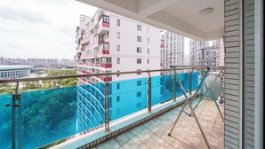 Un rascacielos con balcón de vidrio que da a una piscina azul y un paisaje urbano.