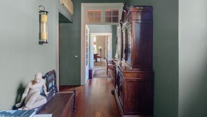 A hallway with a wooden bench, a statue, and a large wooden cabinet.
