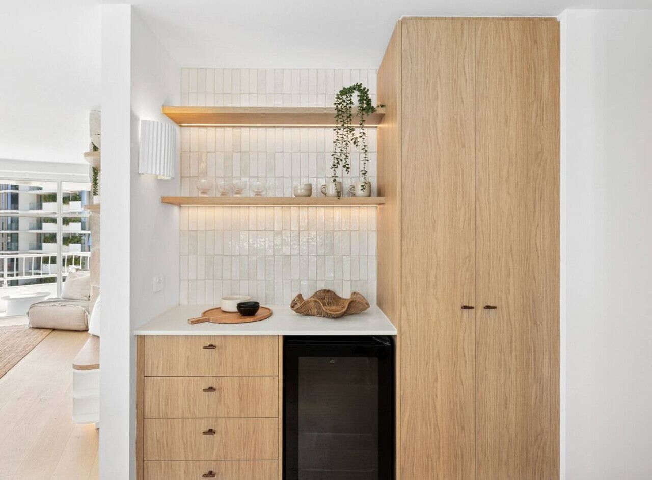 A compact kitchen with white tiled backsplash, wooden cabinets, and a built-in dishwasher.