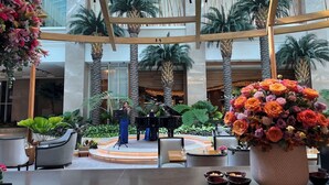 A spacious atrium with a central stage, palm trees, and a large floral arrangement. - Luxurious European Style Modern Apartment Cross City of Dreams OKADA SOLAIRE MOA Airport (Paranaque)