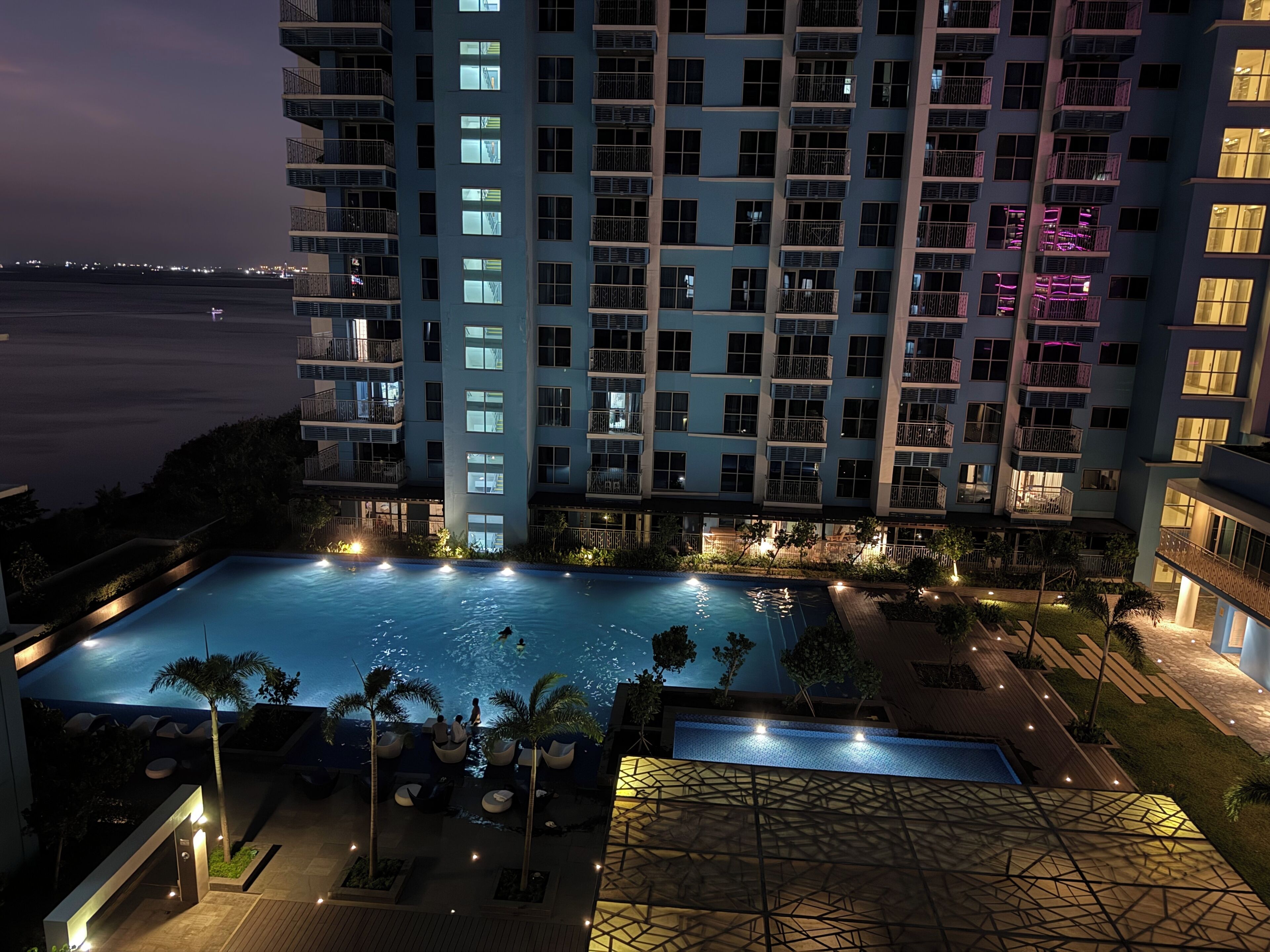 Un hotel de gran altura con piscina, mobiliario exterior y vista al mar.