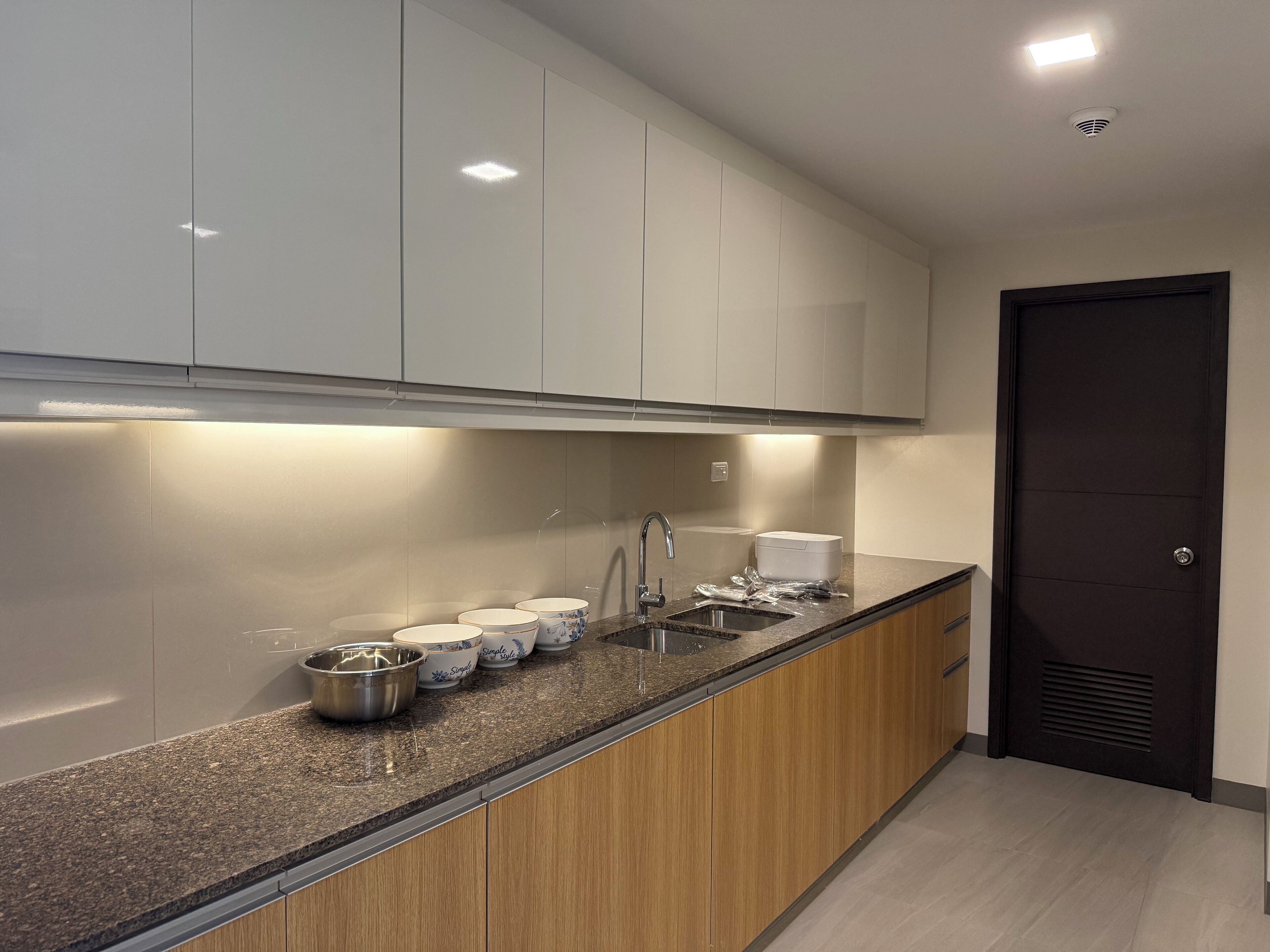 A modern kitchen with white cabinets, a granite countertop, and a stainless steel sink.