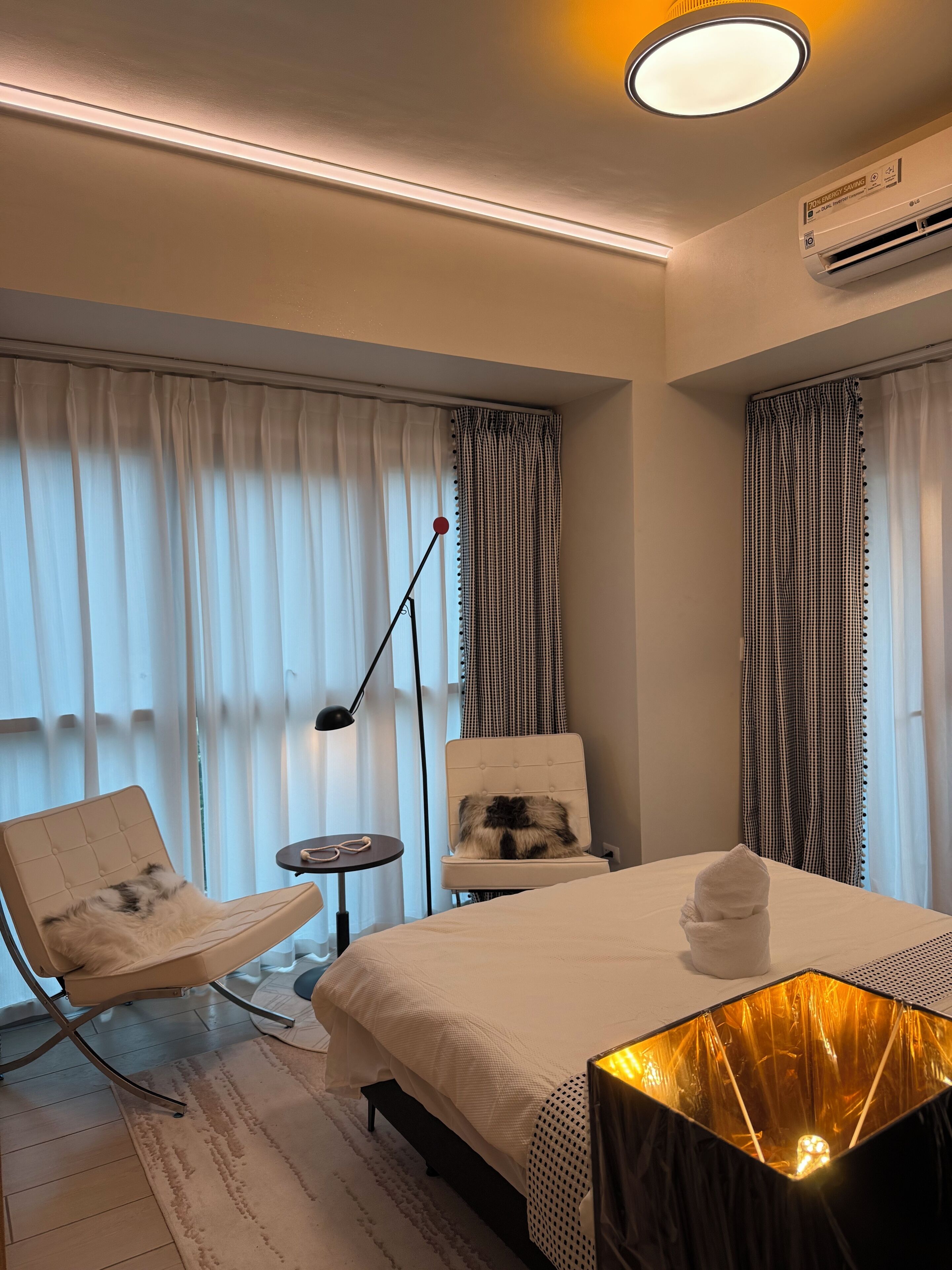 Ein Hotelzimmer mit Bett, Sessel, kleinem Tisch und Klimaanlage.