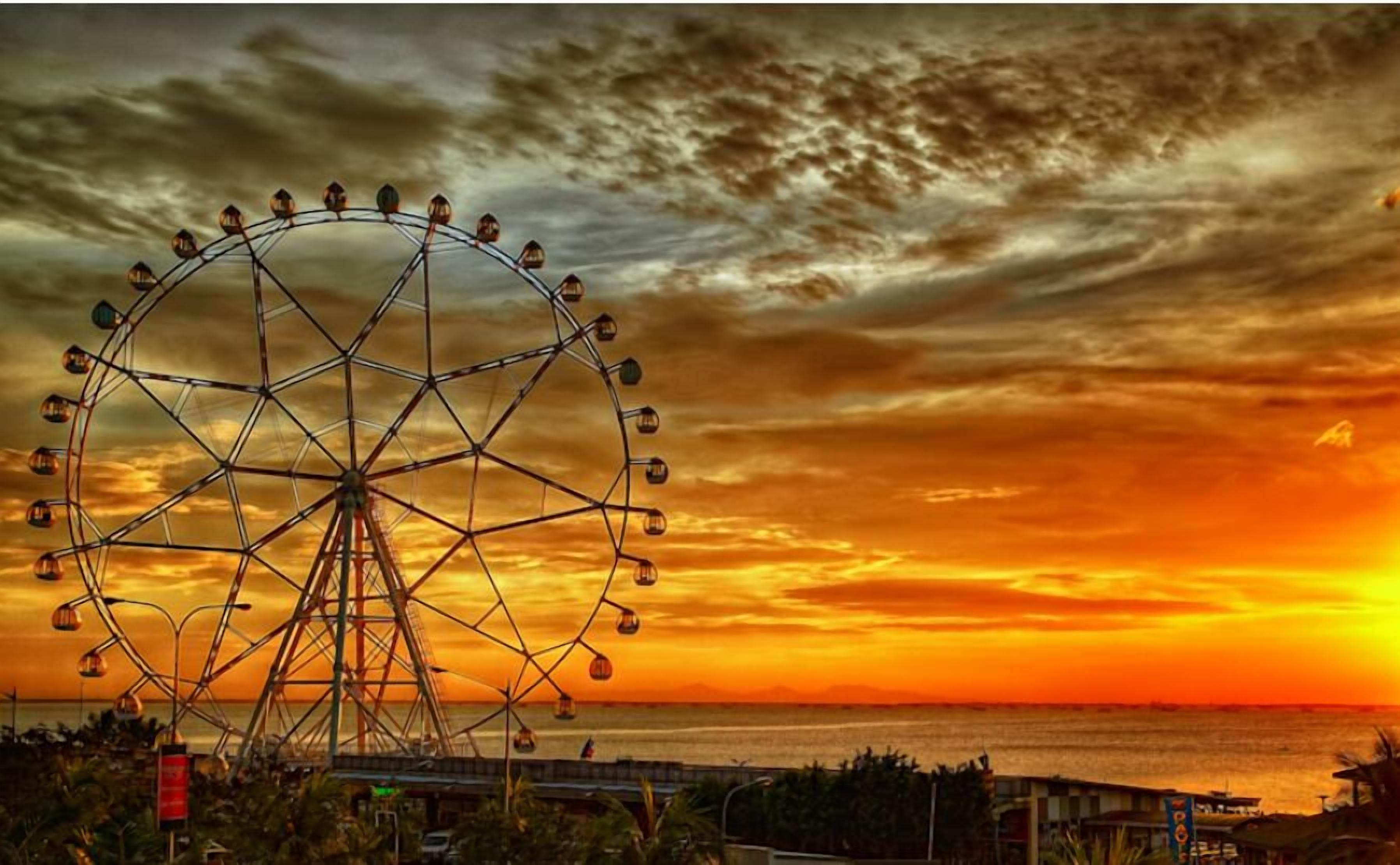Ein Riesenrad bei Sonnenuntergang mit Blick auf das Meer.