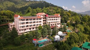 A multi-story hotel with balconies, a swimming pool, and a dome structure. - ECKO Kasang Regency Hill Resort (Lansdowne)