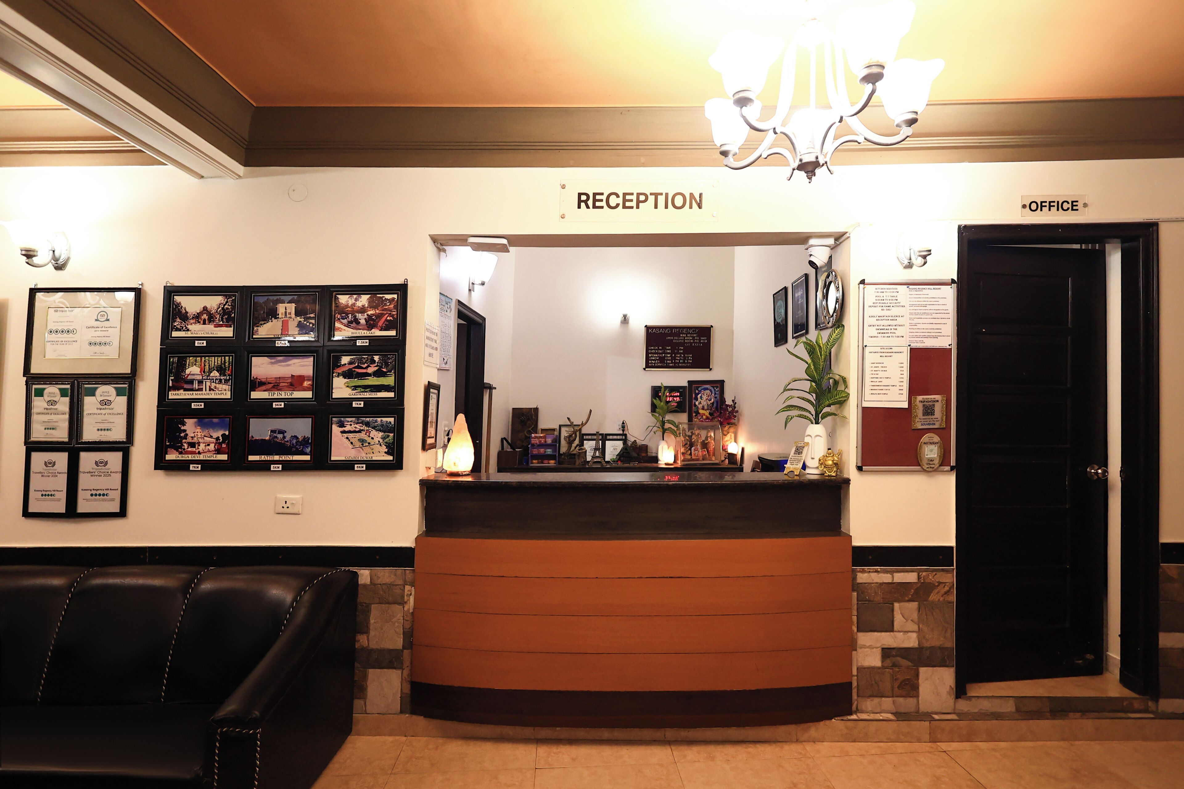 A reception area with a reception desk, framed pictures on the wall, a black door labeled "OFFICE", and a black leather couch.