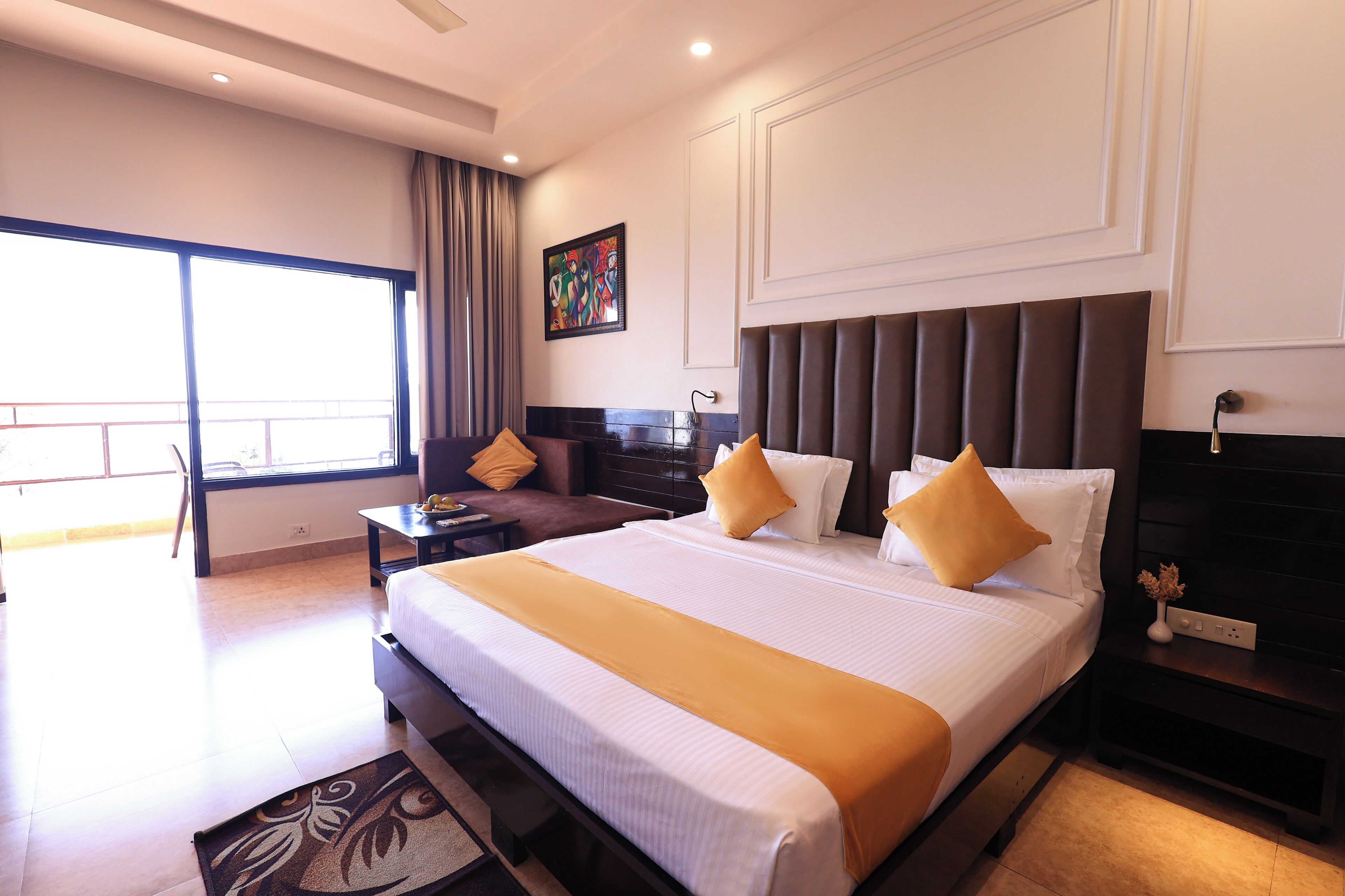 A hotel room with a large bed, a nightstand, a desk, and a window with curtains.