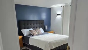 Een slaapkamer met een bed, nachtkastjes en een wandlamp.