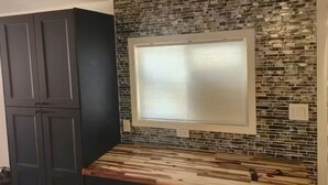 Een keuken met donkere kastjes, een houten aanrechtblad en een spatwand met een mozaïektegelpatroon.