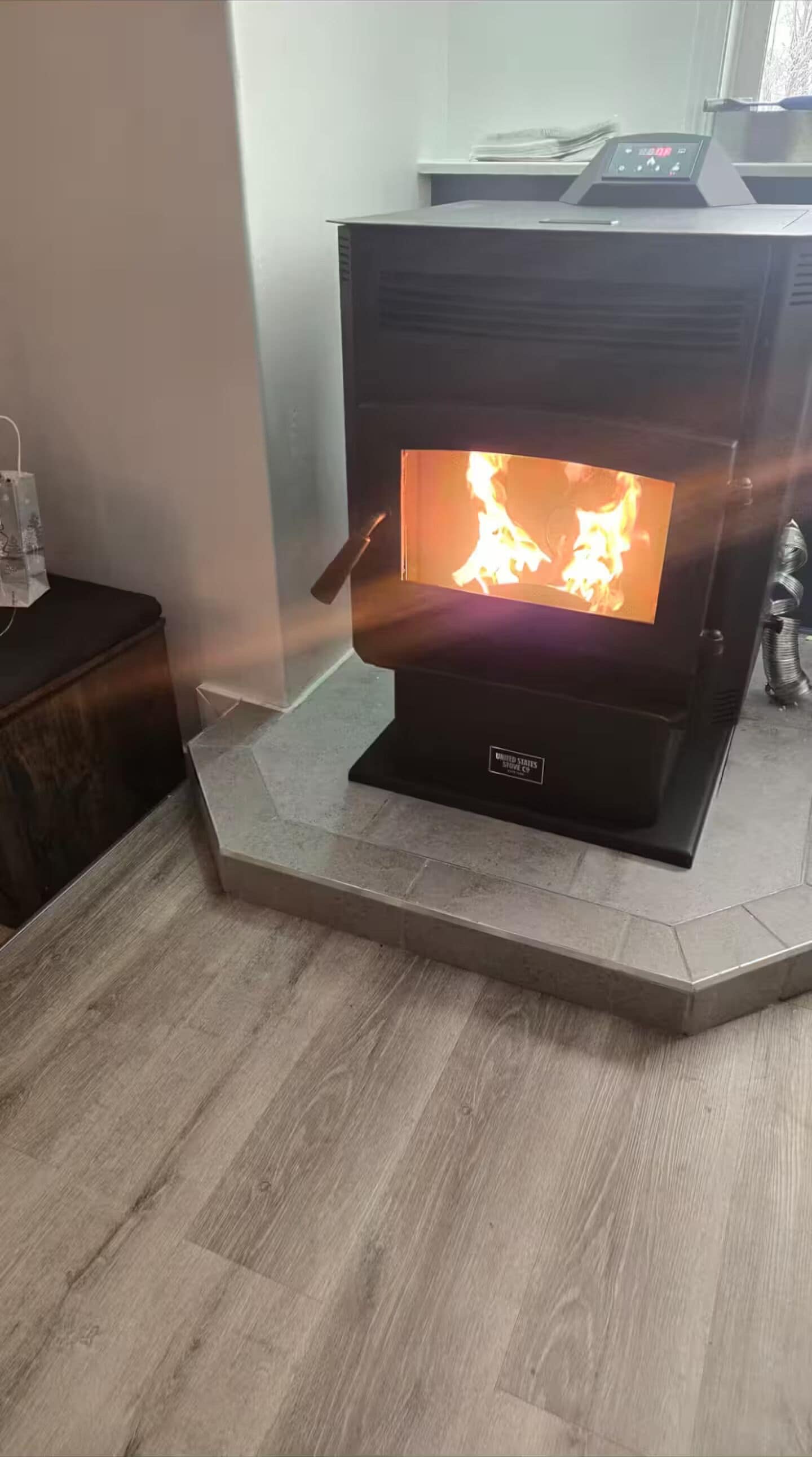 Ein Kaminofen mit sichtbarer Flamme auf einem gefliesten Boden.