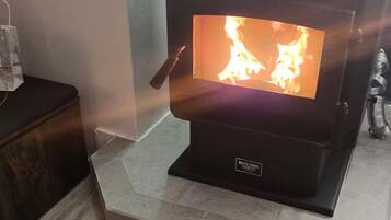 Ein Kaminofen mit sichtbarer Flamme auf einem gefliesten Boden.