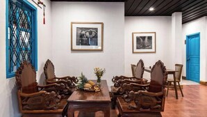 Un comedor con mesa y sillas de madera, obras de arte en las paredes y puertas azules.