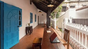 Un espacio al aire libre cubierto con un banco de madera, una computadora portátil y una puerta azul.