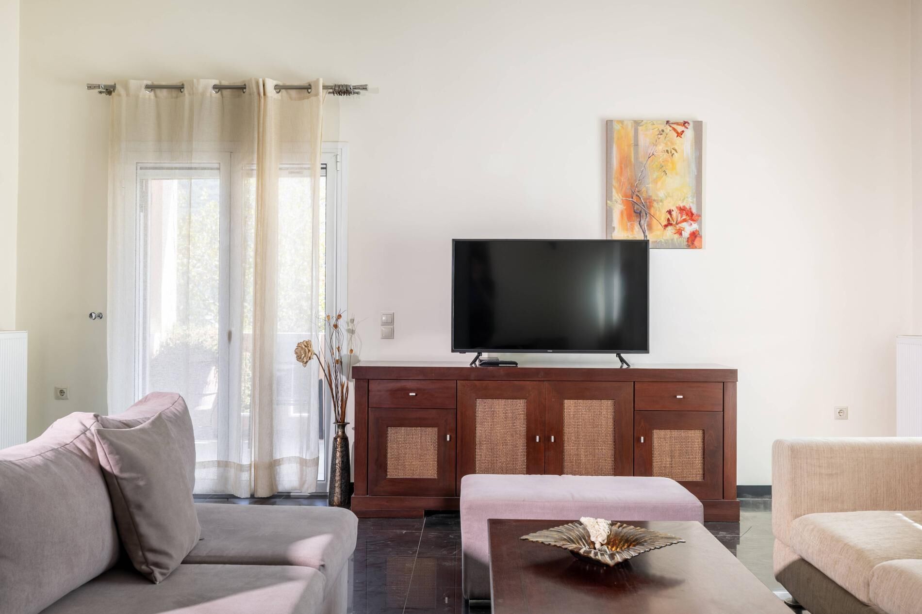 Un salon moderne avec un téléviseur à écran plat, un canapé, une table basse et un meuble.