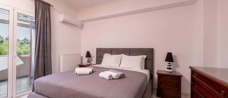 A bedroom with a large bed, two bedside tables, a dresser, and a ceiling light.