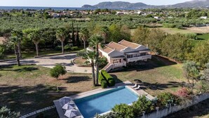 Ett stort hus med en swimmingpool, omgivet av grönska och med utsikt över havet.