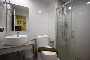 Un baño con lavamanos, inodoro y ducha con cerramiento de vidrio.