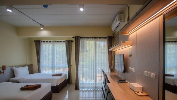 A hotel room with two beds, a desk with a chair, a TV, and a window with curtains. - Wellness World Chiva Khao Yai (Pak Chong)