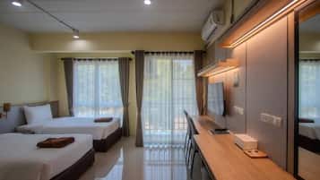 A hotel room with two beds, a desk with a chair, a TV, and a window with curtains.