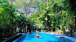 A swimming pool surrounded by lush greenery. - Wellness World Chiva Khao Yai (Pak Chong)