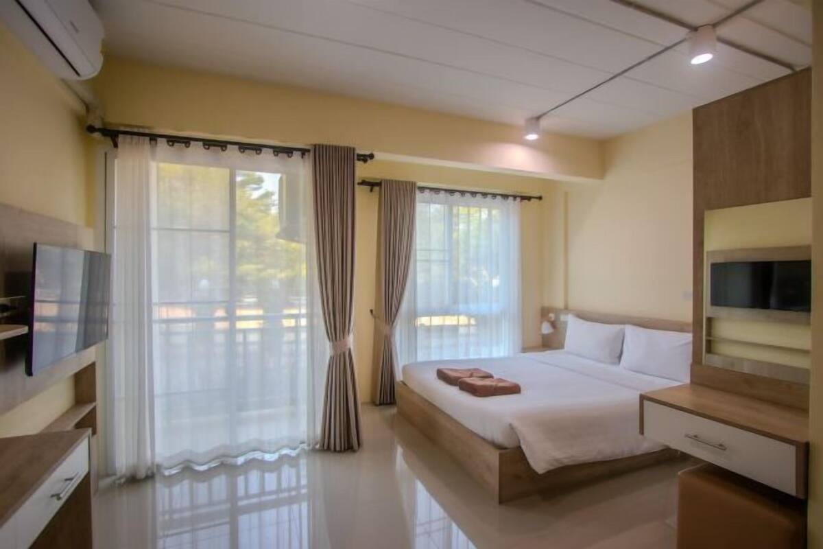 Een hotelkamer met een bed, een televisie, een bureau en een raam met gordijnen.