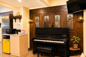 Een piano, een keukenhoek, en een decoratieve wand met ingewikkelde ontwerpen.