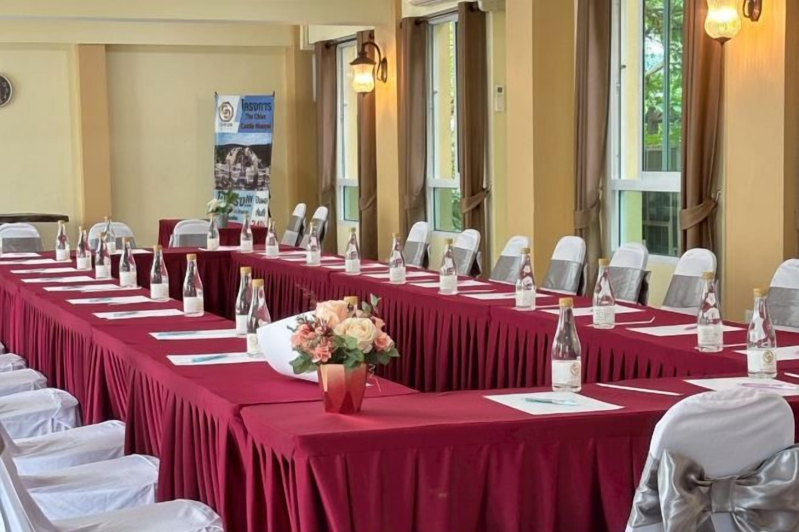 A conference room with a long table, chairs, water bottles, and a flower vase.
