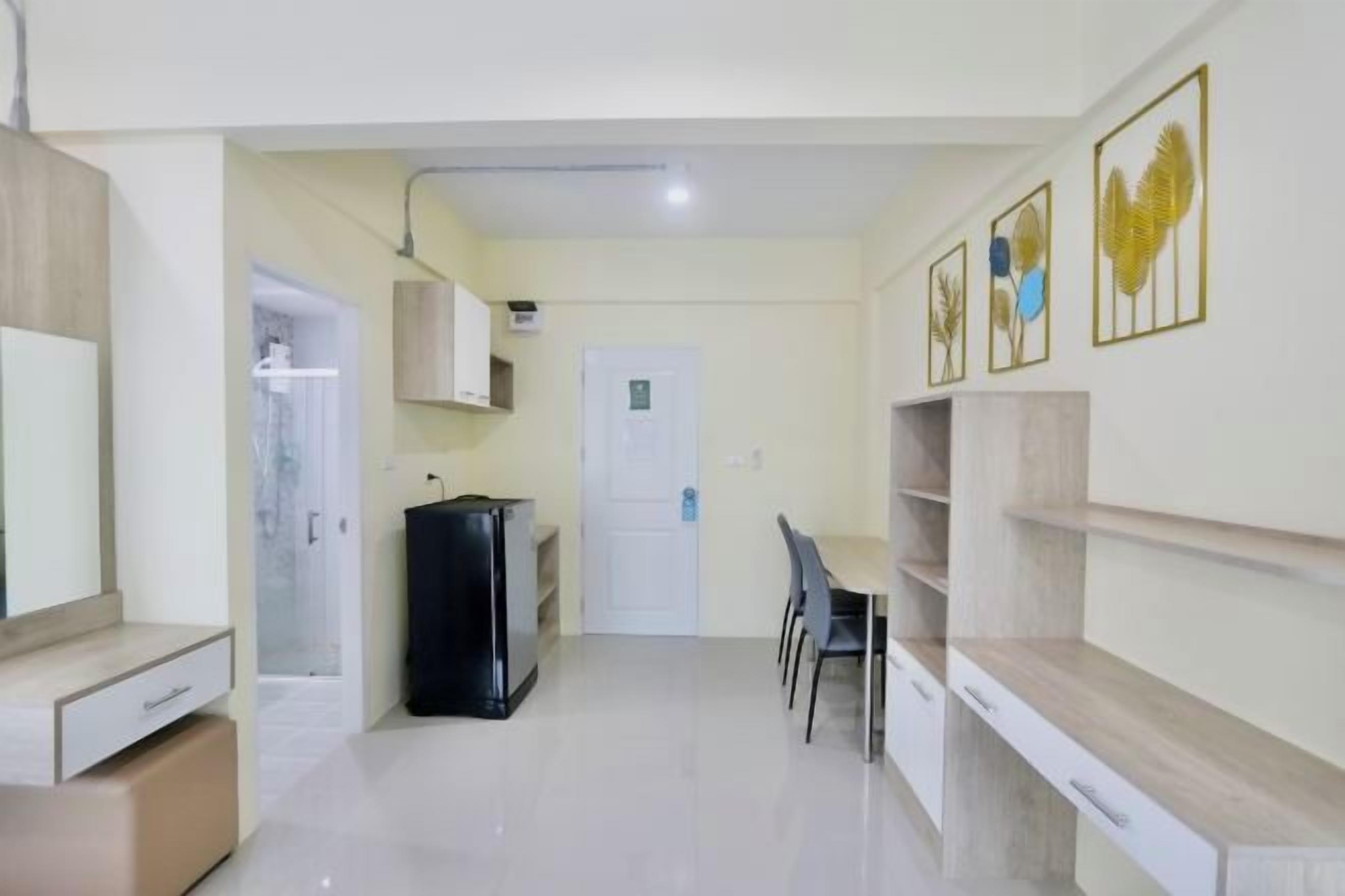 A compact living space with a kitchenette, a dining area, and a door leading to a bathroom.