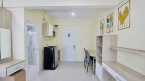 A compact living space with a kitchenette, a dining area, and a door leading to a bathroom. - Wellness World Chiva Khao Yai (Pak Chong)