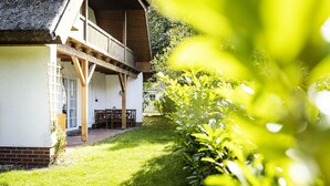 Ein traditionelles Chalet mit Holzbalkon, Strohdach und gepflegtem Garten.
