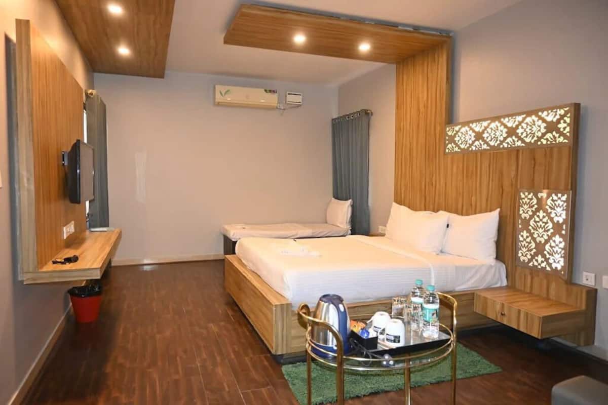 A hotel room with two beds, a TV, a small table with toiletries, and a decorative wall panel.