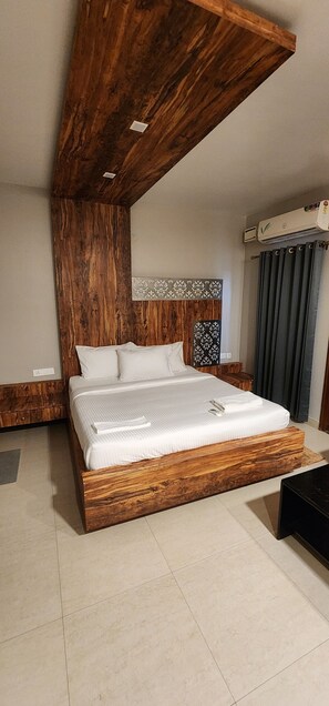 A modern bedroom with a wooden bed frame, a headboard with a patterned design, and a large window with curtains.