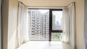 A room with a large window, white curtains, and a view of high-rise buildings. - Tyms 2BR APT Xujiahui Dacheng Residence (Shanghai)