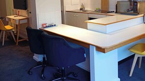 Una cocina compacta con una isla central, un comedor con una silla y una pequeña mesa.