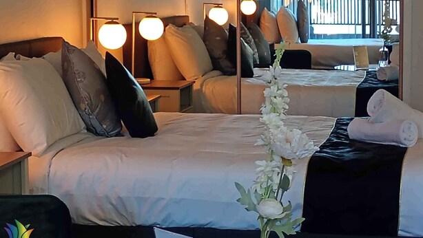 Habitación de hotel con una cama grande, una mesita de noche, un espejo y vistas al balcón exterior.
