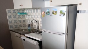 A compact kitchen with a built-in dishwasher, a stainless steel refrigerator, and a patterned backsplash. - Apartment resort ÔMyrtilles (Besse-et-Saint-Anastaise)