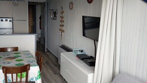 A compact living space with a dining area, kitchenette, and a TV mounted on the wall. - Apartment resort ÔMyrtilles (Besse-et-Saint-Anastaise)