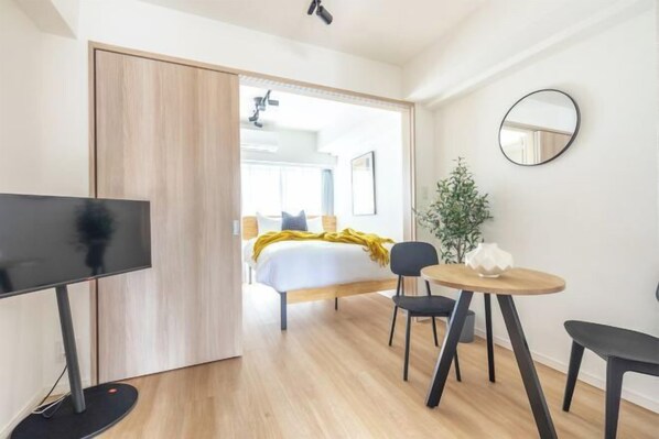 A modern hotel room with a bed, a TV, a dining table, and a mirror. - Dash Living Asakusa East (Tokyo)