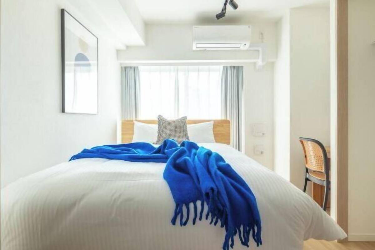 Quarto de hotel com cama, uma cadeira e janela com cortinas.