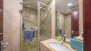 A modern bathroom with a glass-enclosed shower, a sink with a mirror, and a towel rack. - Tyms Xuhui Elegant 1BR APT  (Shanghai)