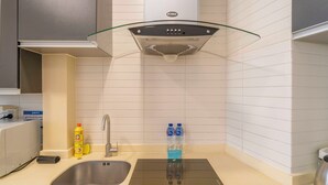 A modern kitchen with a stainless steel sink, a glass-top stove, and a built-in range hood. - Tyms Xuhui Elegant 1BR APT  (Shanghai)