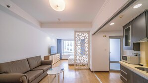 A modern living room with a sofa, a small table, and a decorative partition. - Tyms Xuhui Elegant 1BR APT  (Shanghai)