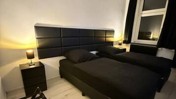 A modern bedroom with a large bed, bedside tables, and a wooden chair.