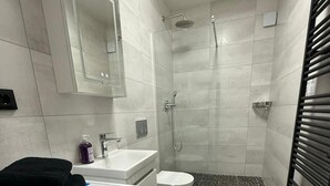 A modern bathroom with a washing machine, a toilet, a sink, and a shower.