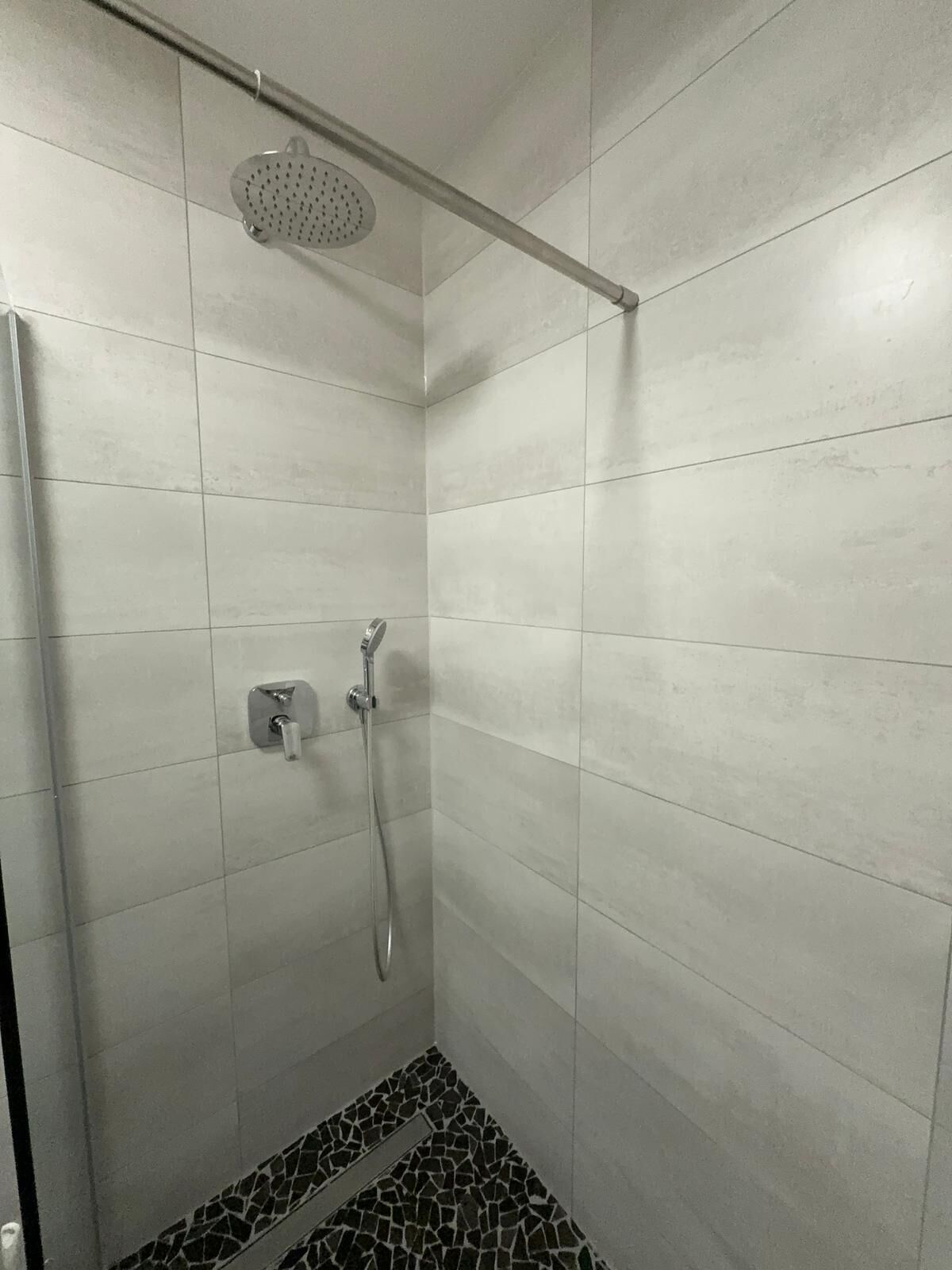 Een douche met een handdouche en een wandmengkraan.