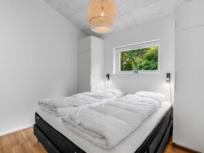 Une chambre moderne avec un lit, une fenêtre donnant sur un paysage verdoyant et un luminaire au plafond au design original.