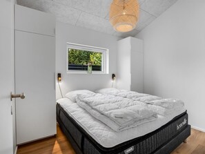 Et soveværelse med en seng, et vindue med udsigt til grønne omgivelser og en lampe i loftet.