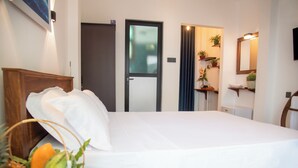 A neatly made bed in a room with a wooden headboard, a basket of fruit, and a mirror on the wall. - Villa Roberocia  (Hikkaduwa)