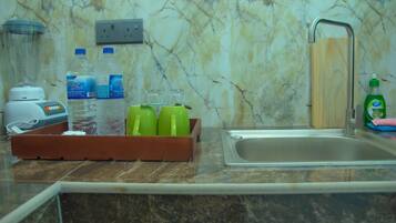 A kitchen counter with a marble backsplash, a sink, and a wooden tray holding water bottles and glasses.