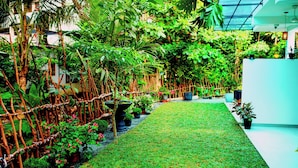 A lush indoor garden with a variety of plants, a neatly trimmed lawn, and a modern building structure in the background. - Villa Roberocia  (Hikkaduwa)
